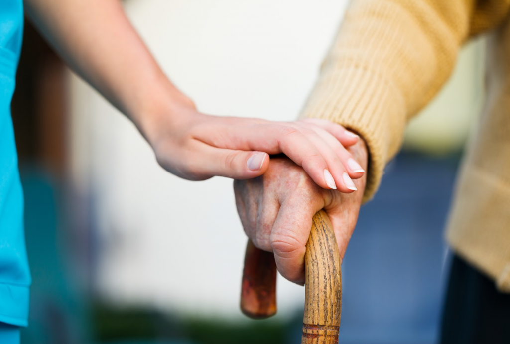 A woman holding another's hand in a caring manner.